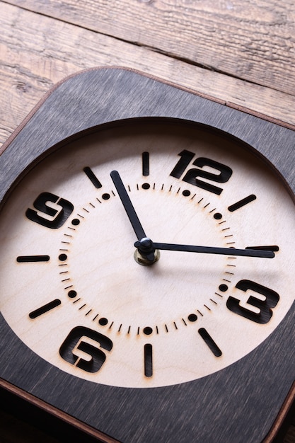 Reloj de madera hecho a mano en mesa de madera. De cerca.