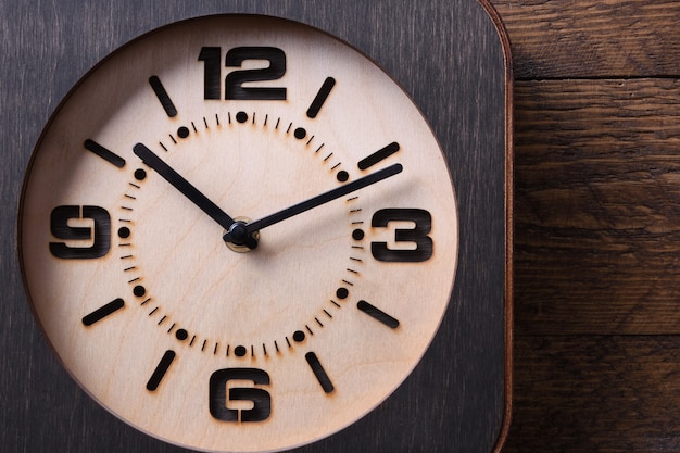 Reloj de madera hecho a mano en mesa de madera. De cerca.