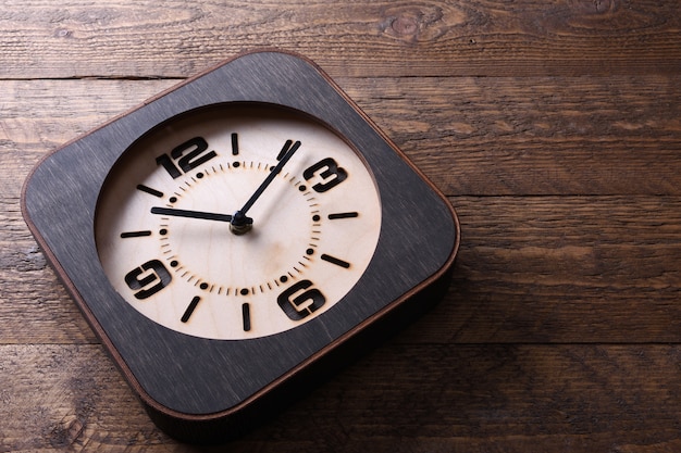 Foto reloj de madera hecho a mano en mesa de madera. de cerca.