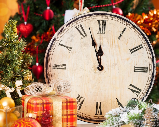 Reloj de madera vintage contra adornos para árboles de Navidad