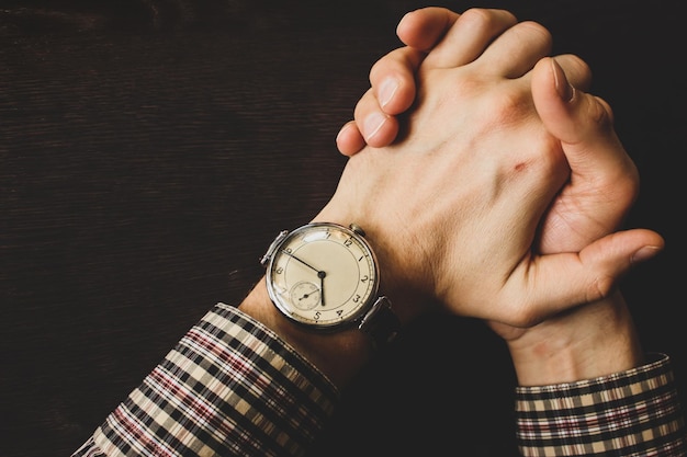 Foto reloj de mano vintage en la mano del hombre dedos apretados concepto de tensión reloj retro en la mano