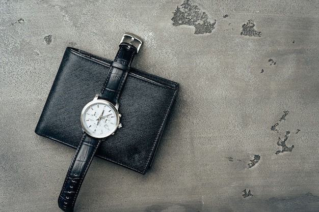 Reloj masculino y billetera de cuero sobre superficie gris oscuro cerrar