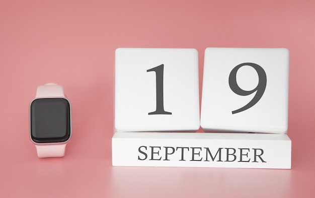 Reloj moderno con calendario de cubo y fecha 19 de septiembre en pared rosa. Concepto tiempo de vacaciones de otoño.