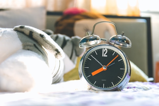 El reloj y la muñeca en la cama muestran las ocho de la mañana