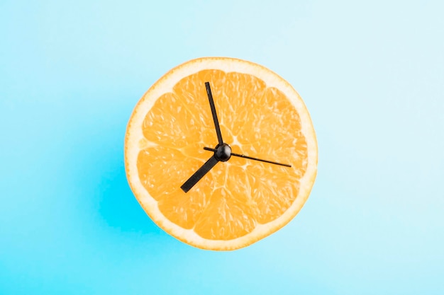 Reloj naranja real sobre fondo azul.