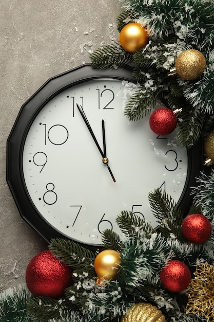 Reloj de Navidad con decoración navideña sobre fondo gris. Feliz año nuevo concepto. Foto vertical.