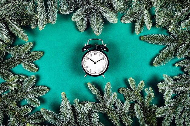 Reloj negro sobre fondo verde con ramas de Navidad