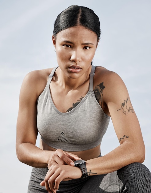 Este reloj no solo indica la hora Foto de una joven deportista revisando su reloj inteligente mientras hace ejercicio al aire libre