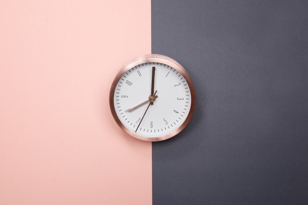 Reloj de oro rosa sobre fondo rosa pastel y gris. concepto de negocio de idea mínima.