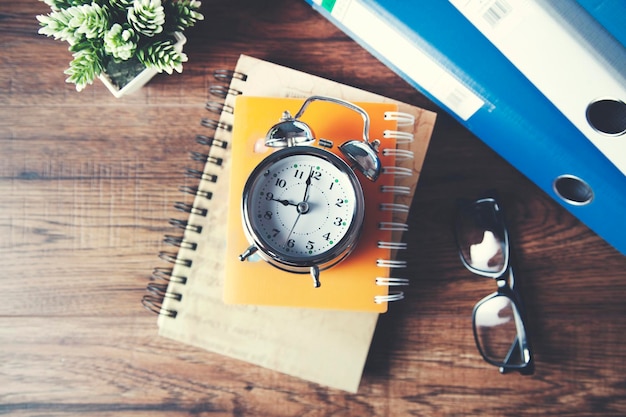 Reloj con papelería en la mesa.