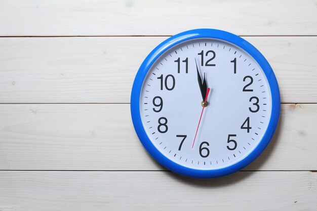 Reloj de pared azul con hora de medianoche en la pared de madera