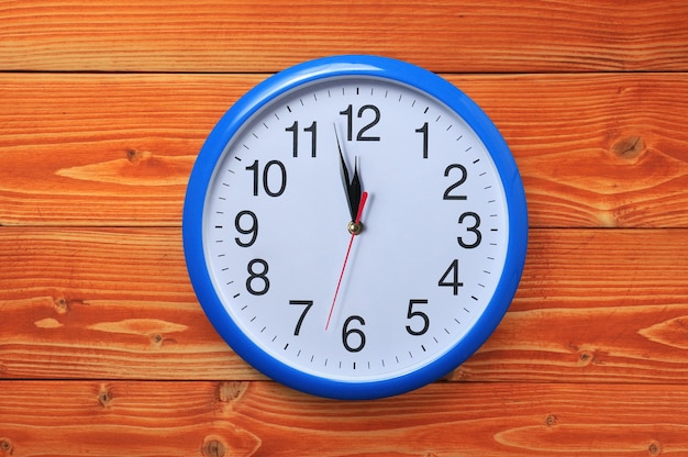 Reloj de pared azul con hora de medianoche en la pared de madera