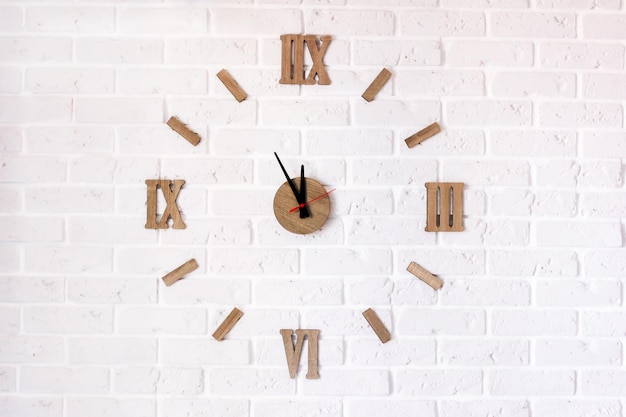 Reloj de pared de diseño creativo con esfera de madera sobre una pared de ladrillo blanco. concepto de tiempo