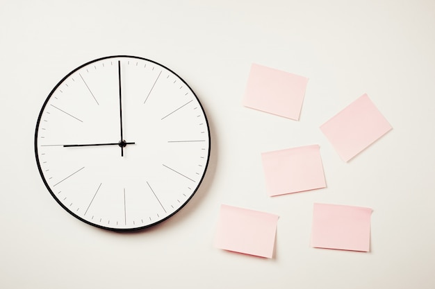 Reloj de pared y pegatinas rosas sobre un fondo blanco.