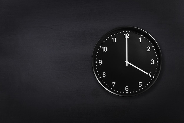 Reloj de pared que muestra las cuatro en punto sobre fondo de pizarra negra Reloj de oficina que muestra las 4 a.m. o las 4 p.m. en textura negra
