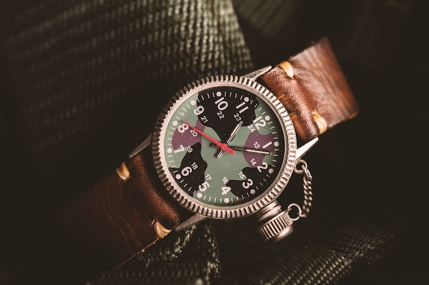 Reloj de pulsera de estilo militar antiguo con esfera de camuflaje y correa de piel.