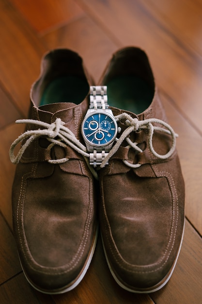 Reloj de pulsera para hombre encima de zapatos de ante marrón para hombre