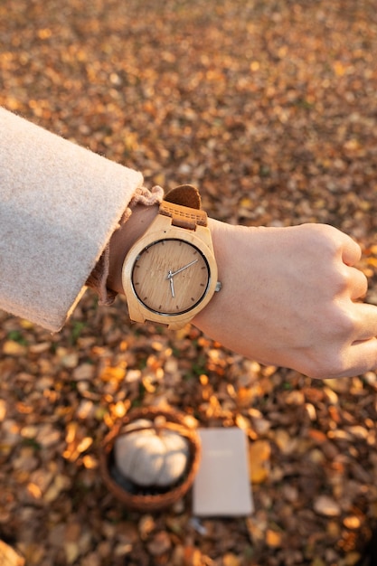 Reloj de pulsera de madera en el brazo de una niña frente a un fondo de hojas de otoño