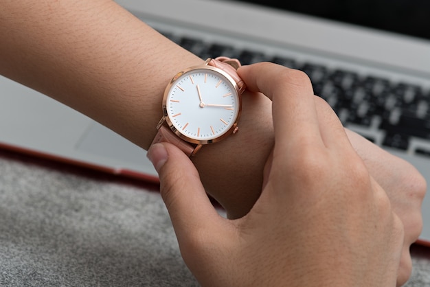 Foto reloj de pulsera en la mano de la niña frente a una computadora portátil