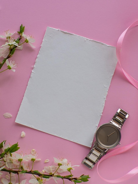 Reloj de pulsera para mujer sobre fondo rosa con flores de cerezo y espacio para copiar