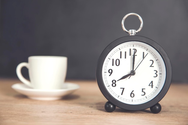 Reloj con taza de café en el escritorio