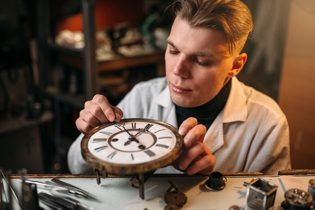 Relojero ajusta el mecanismo de los relojes antiguos