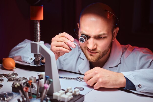 El relojero experimentado está grabando el reloj de un cliente en su taller.