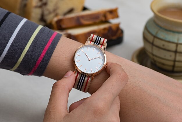 Relojes de pulsera en la mano de la niña en el descanso para tomar café