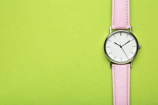 Relojes de pulsera rosa sobre fondo verde con espacio de copia