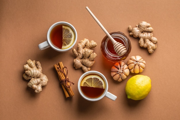 Remedios caseros naturales para el resfriado y la gripe: tazas de té caliente con limón, miel, jengibre y ajo para estimular el sistema inmunológico. Ingredientes alimentarios naturales y saludables para estimular la inmunidad y contra los virus. Vista superior