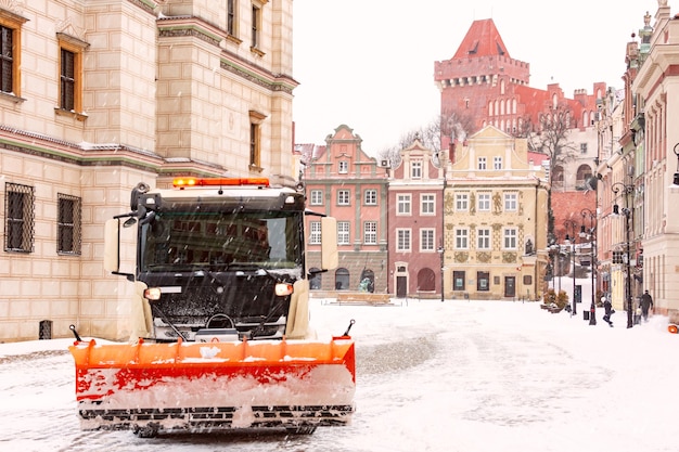 Remoção de neve e limpeza de ruas em poznan. castelo real e praça do mercado velho na cidade velha em dia de inverno nevado, poznan, polônia