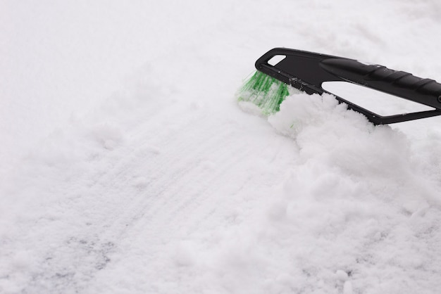 Remoción de nieve, coche en nieve. La mujer limpia el coche de la nieve.