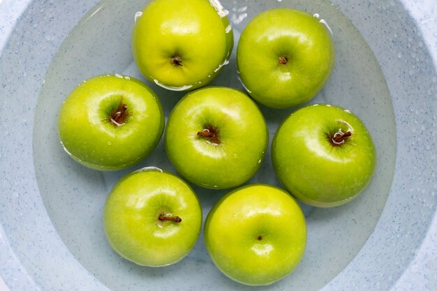 Remojar las manzanas verdes en agua. Concepto de lavado de frutas