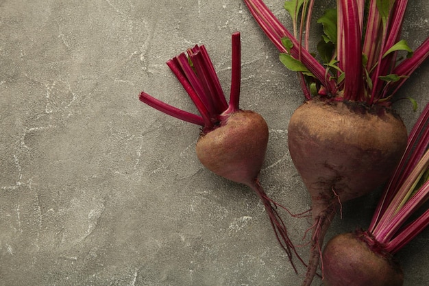 Remolacha roja con hojas verdes sobre fondo gris Remolacha orgánica