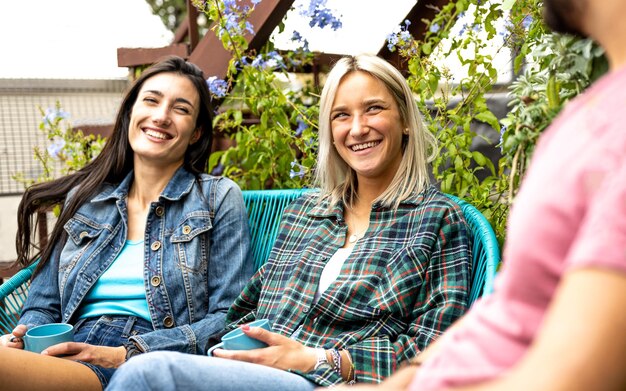 Remolcar mujeres jóvenes hablando y charlando en la cafetería del bar con un hombre de la generación z personas divirtiéndose en una reunión social chicas rubias y morenas sonriendo a un amigo