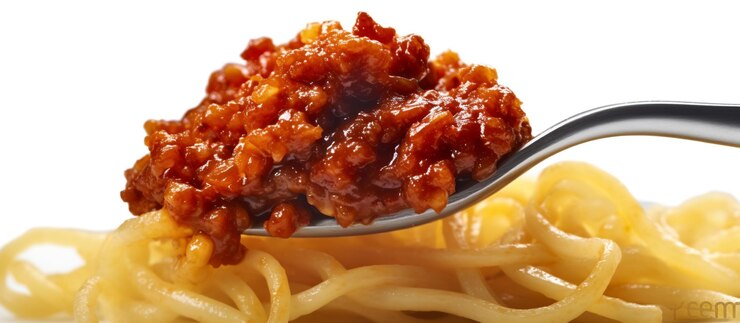 Un remolino de espagueti con carne picada y escamas de chile rojo en un tenedor