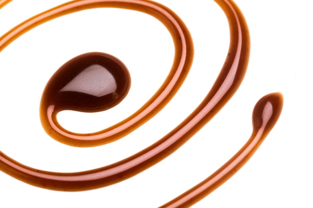 Remolino de salsa de caramelo de chocolate sobre un fondo blanco liso