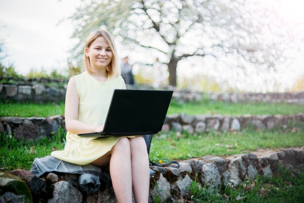 Remote-Arbeit junge Frau arbeitet mit einem Laptop in einem Park in der Natur Selbstisolation und Internetarbeit