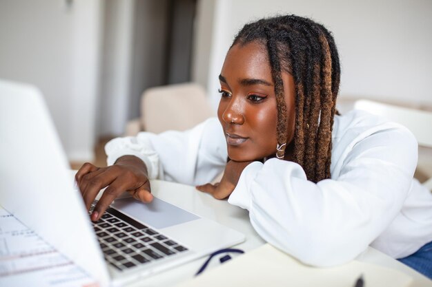 Remote-Job-Technologie und People-Konzept Junge afrikanische Geschäftsfrau mit Laptop-Computer und Papieren, die während der Covid19-Gesundheitskrise im Home Office arbeiten