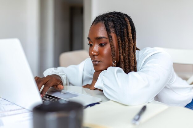 Remote-Job-Technologie und People-Konzept Junge afrikanische Geschäftsfrau mit Laptop-Computer und Papieren, die während der Covid19-Gesundheitskrise im Home Office arbeiten