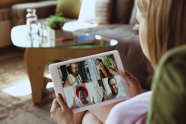 Remote-Meeting. Frauen, die während der Quarantäne von Coronavirus oder COVID-19 von zu Hause aus arbeiten, Remote-Office-Konzept. Junger Chef, Manager vor Tablet während Online-Konferenz mit Kollegen und Team.