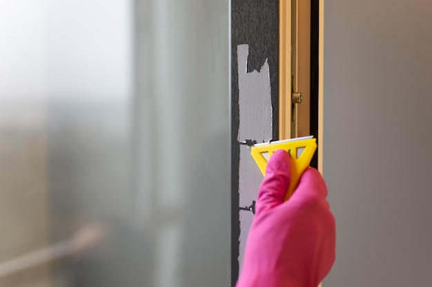Removendo a fita protetora da moldura da janela com raspador