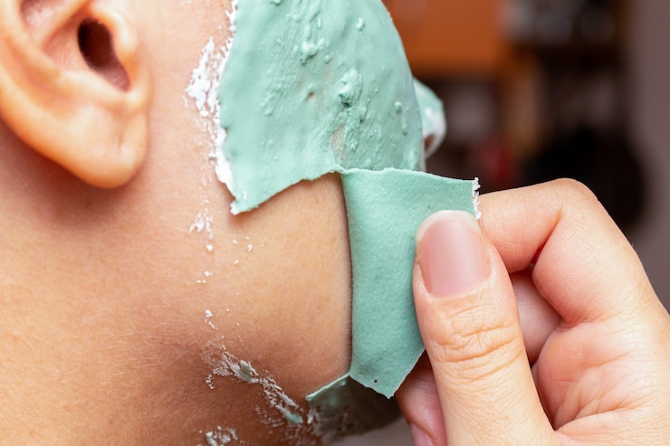 Foto removendo uma máscara de argila cosmética verde do rosto da mulher