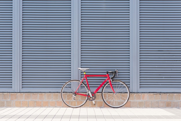 Rennrotes Fahrrad steht auf einer grauen Wand