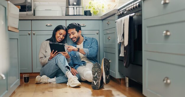 Foto renovación de una casa nueva y pareja con tableta digital en el suelo de la cocina para la búsqueda de ideas o inspiración propiedad inmobiliaria y hombre con mujer en línea para planificación creativa y diseño de interiores