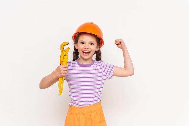 Renovación en la habitación de los niños Un niño en un casco de construcción y una llave inglesa sobre un fondo blanco aislado Trabajar como constructor eligiendo una profesión para un niño