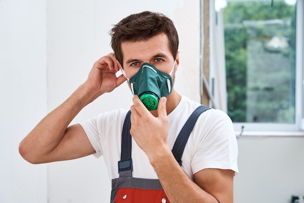 Renovierungshandwerker setzt Atemschutzgerät auf. Porträt des Hausreparaturarbeiters