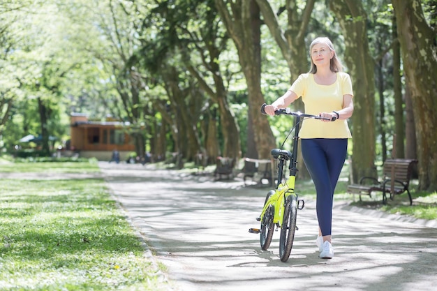 Rentnerin, die sich im Park ausruht Grauhaarige Perserin geht an einem Sommertag mit dem Fahrrad spazieren