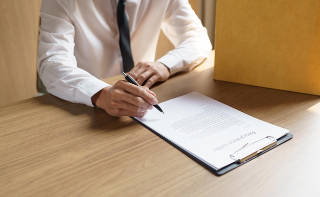 Foto renunciar al trabajo hombre de negocios enviando una carta de renuncia y empacando cosas renunciar deprimir o llevar una caja de cartón comercial en la oficina cambio de trabajo o despedido de la empresa