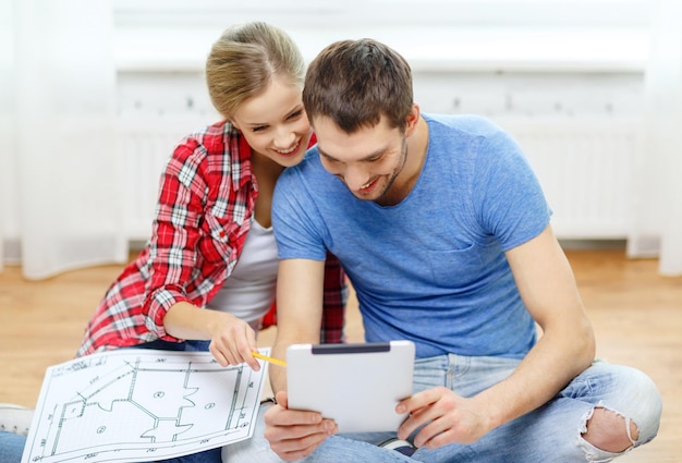 Foto reparação, construção, renovação e conceito de casa - casal sorridente olhando para tablet pc em casa